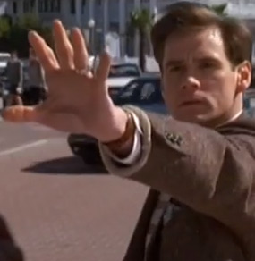 Jim Carrey nel film Truman Show è in strada ed ha il braccio sinistro allungato verso di noi con la mano aperta in segno di voler fermare qualcosa