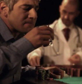 Un uomo ad un tavolo da gioco beve controvoglia un bicchiere di sciroppo osservato da un croupier con camice medico e stetoscopio