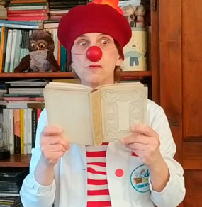 Un Clown Dottore legge un libro con un'espressione di stupore
